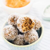 A pile of no bake carrot cake energy bites in a blue bowl.
