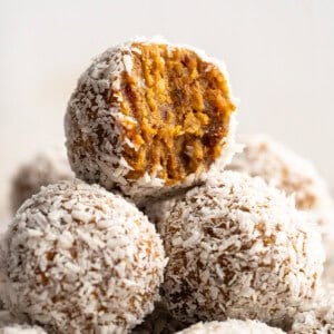 Stack of carrot cake no bake energy bites with top bitten into.