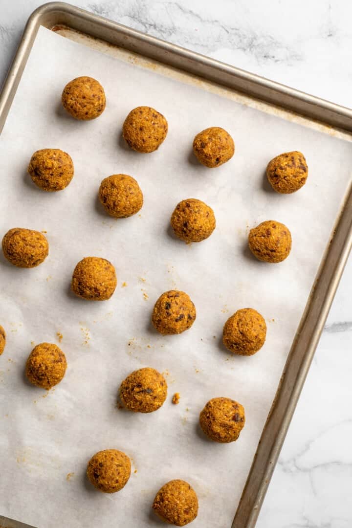 These no bake carrot cake energy bites are cozy, warmly spiced, and wholesome since they're made with nuts, carrots and dates for sweetness! Carrot cake no bake energy bites on parchment lined pan.