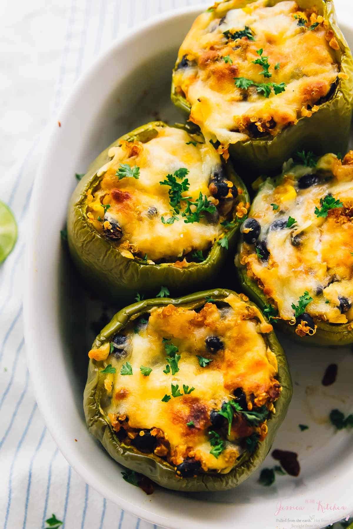 Overhead shot of four quinoa stuffed peppers in a baking dish.