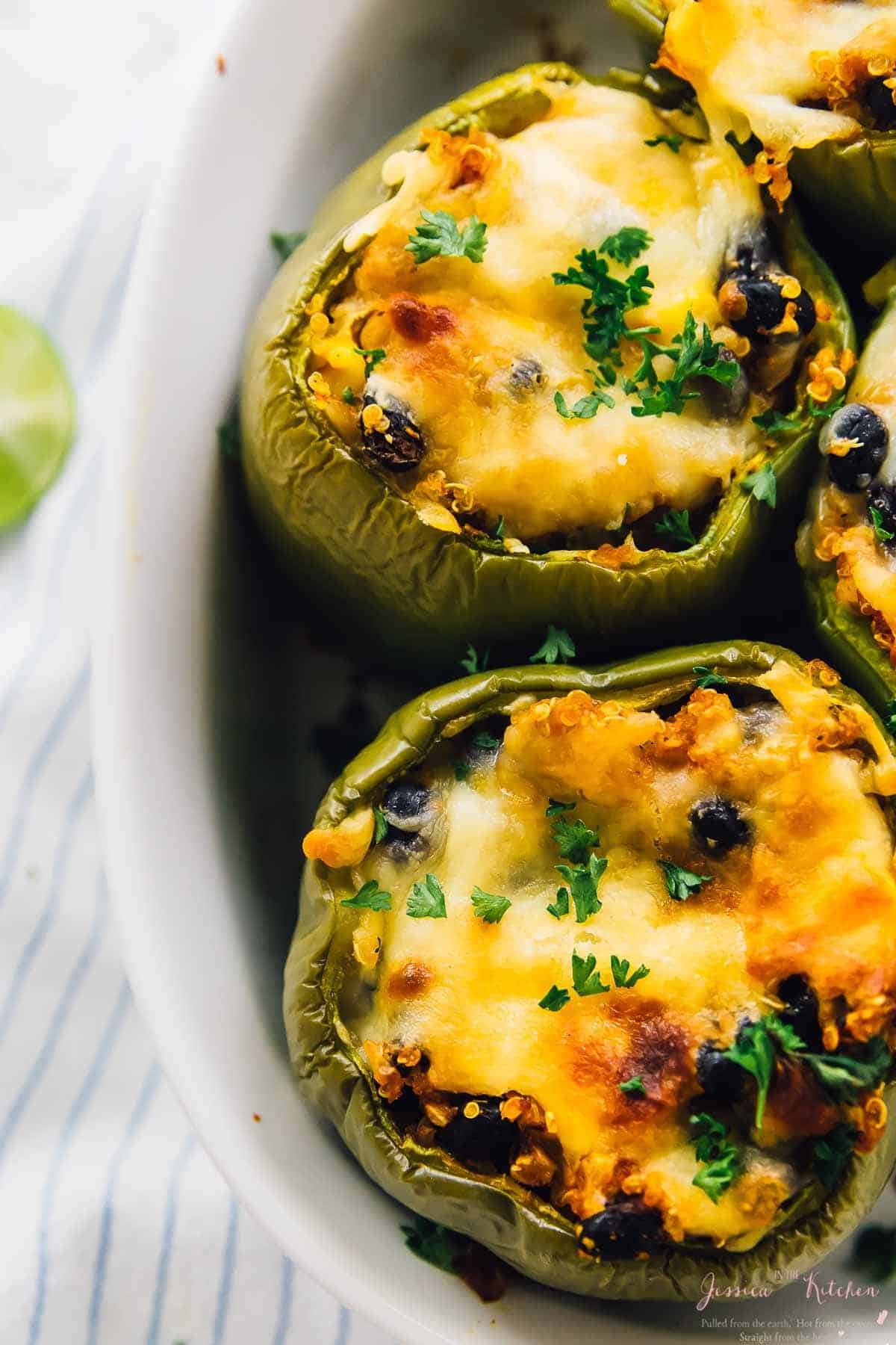 Close up of quinoa stuffed peppers in a white baking dish.