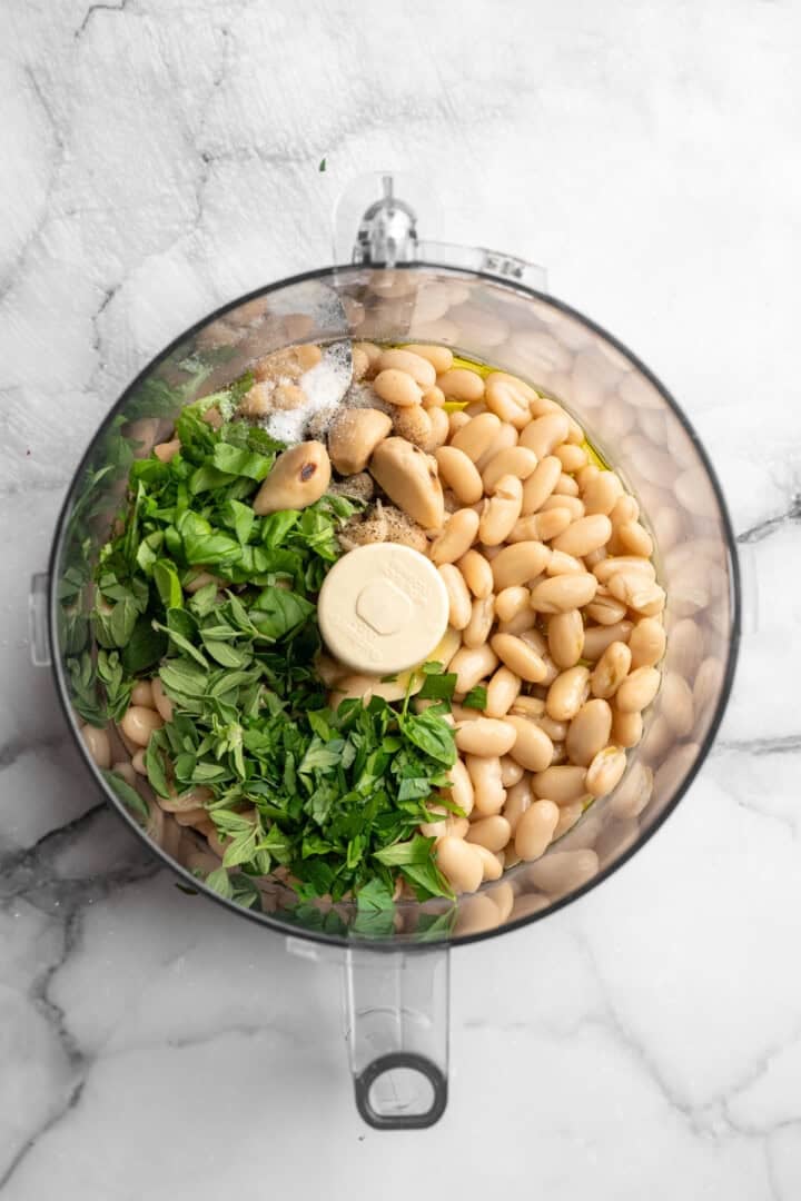 Ingredients for roasted garlic white bean dip in food processor.