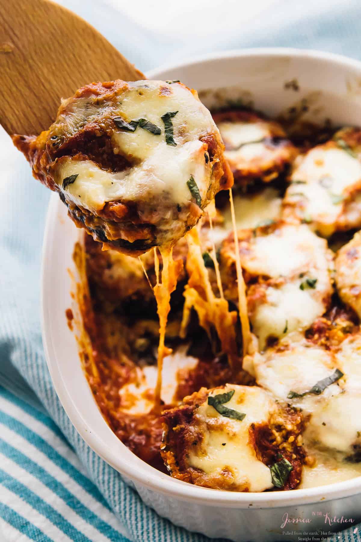 Baked eggplant scooped out of a baking dish with a spatula