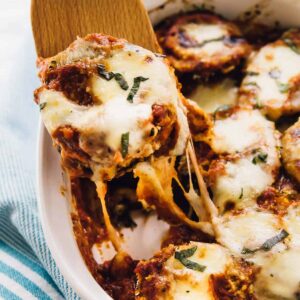 Baked eggplant scooped out of a baking dish with a spatula