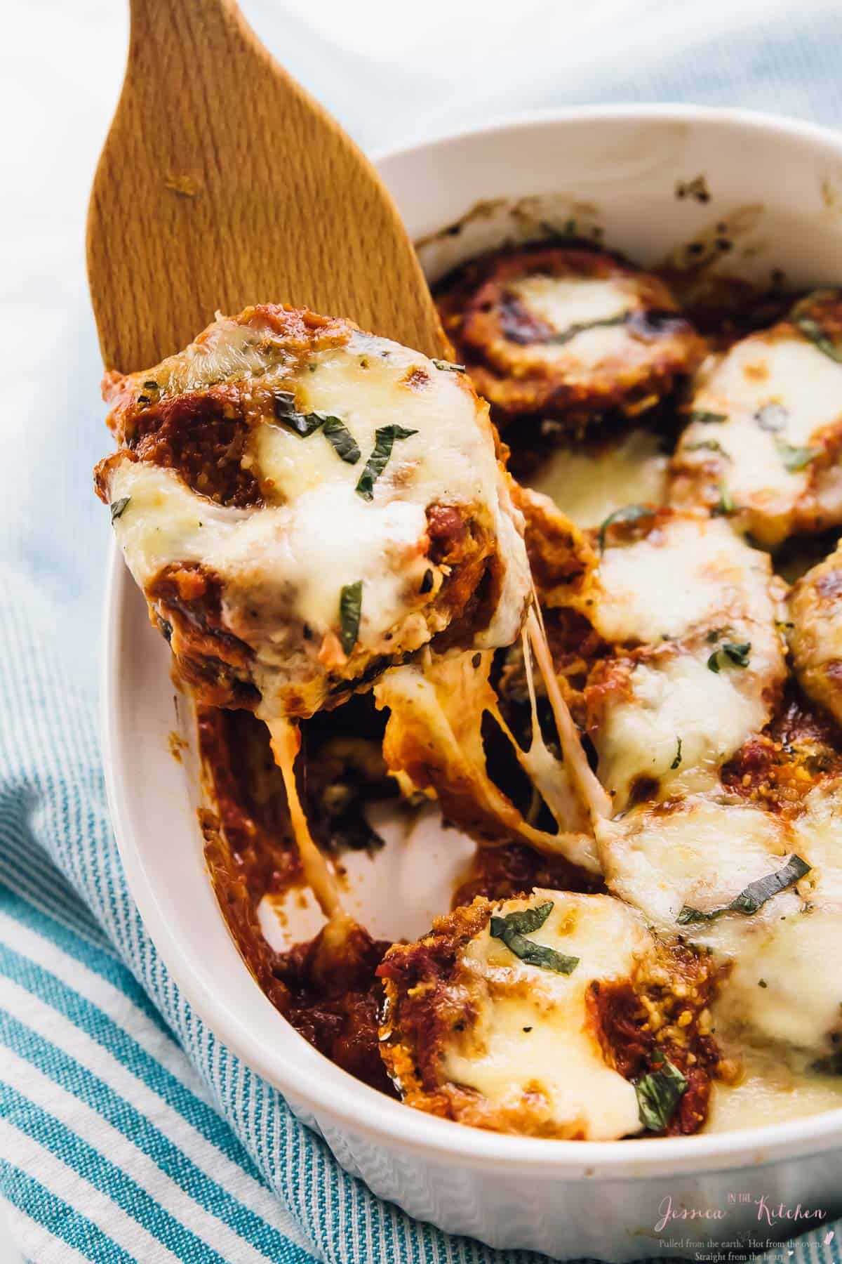 Baked eggplant scooped out of a baking dish with a spatula