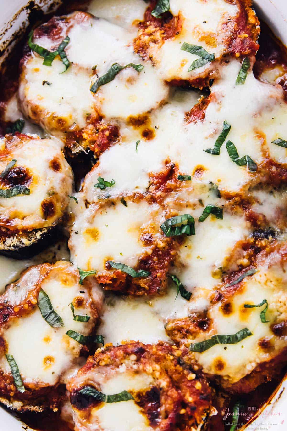 Top down shot of baked eggplant parmesan in a baking dish. 