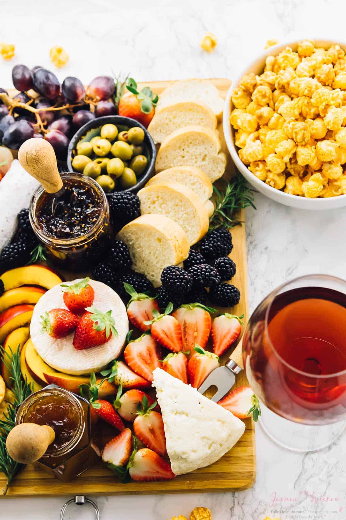 Overhead shot of cheeseboard with a bowl of popcorn on the side. 