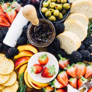 Top down shot of cheeseboard with fruit, jam and olives.