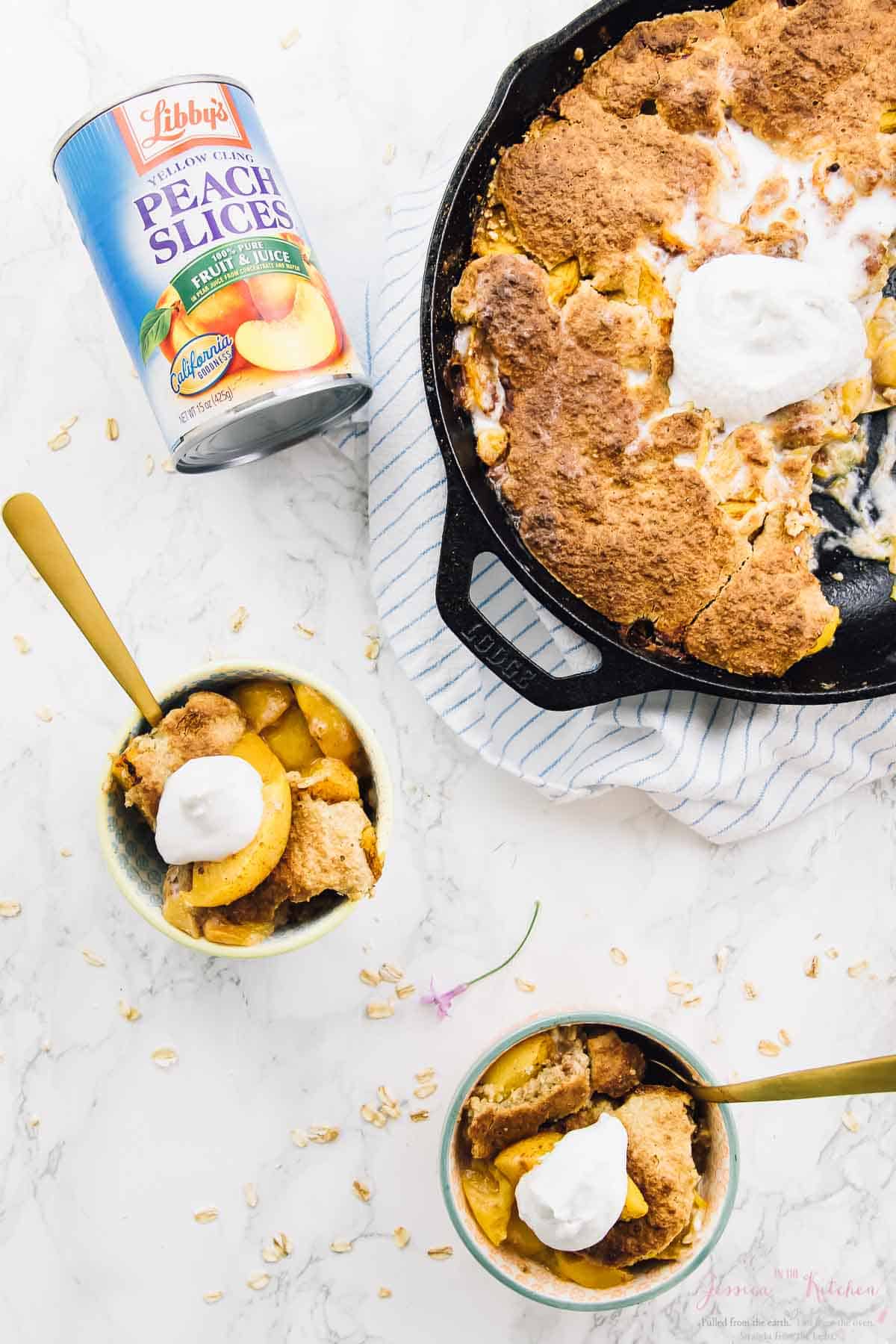 Peach cobbler in two bowls and a black skillet. 