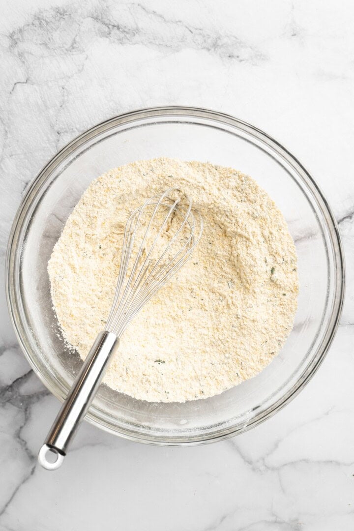 Dry ingredients for cornbread waffles in bowl with whisk