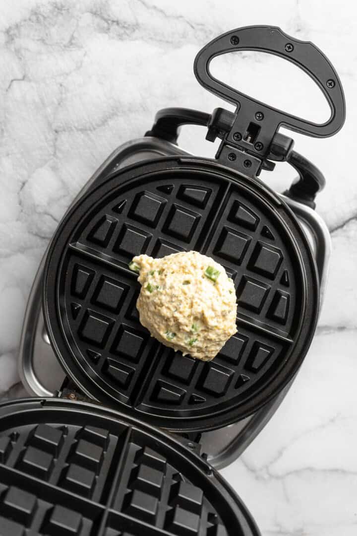 Overhead view of cornbread waffle batter in waffle iron