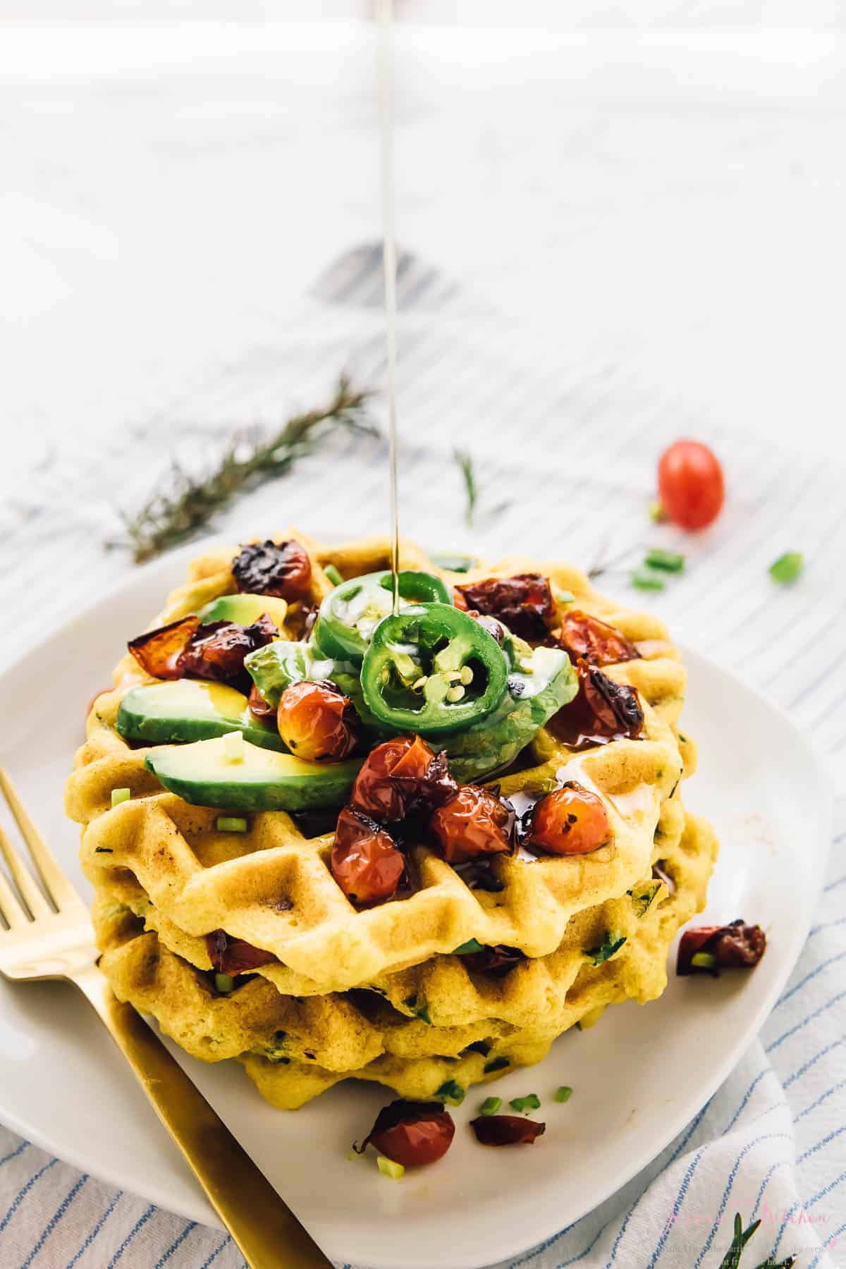 A stack of cornbread waffles drizzled with syrup. 