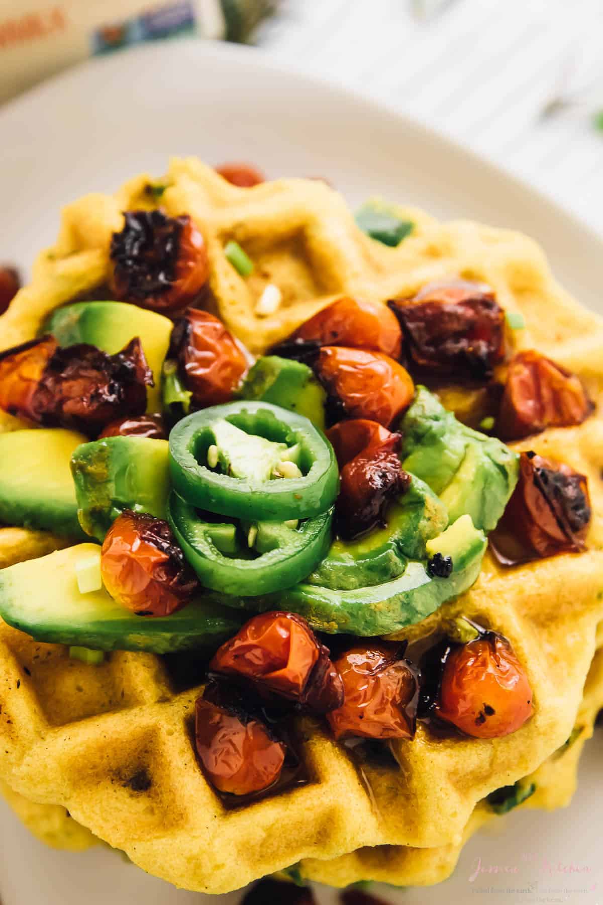 A close up of cornbread waffles with sliced jalapeno's on top. 