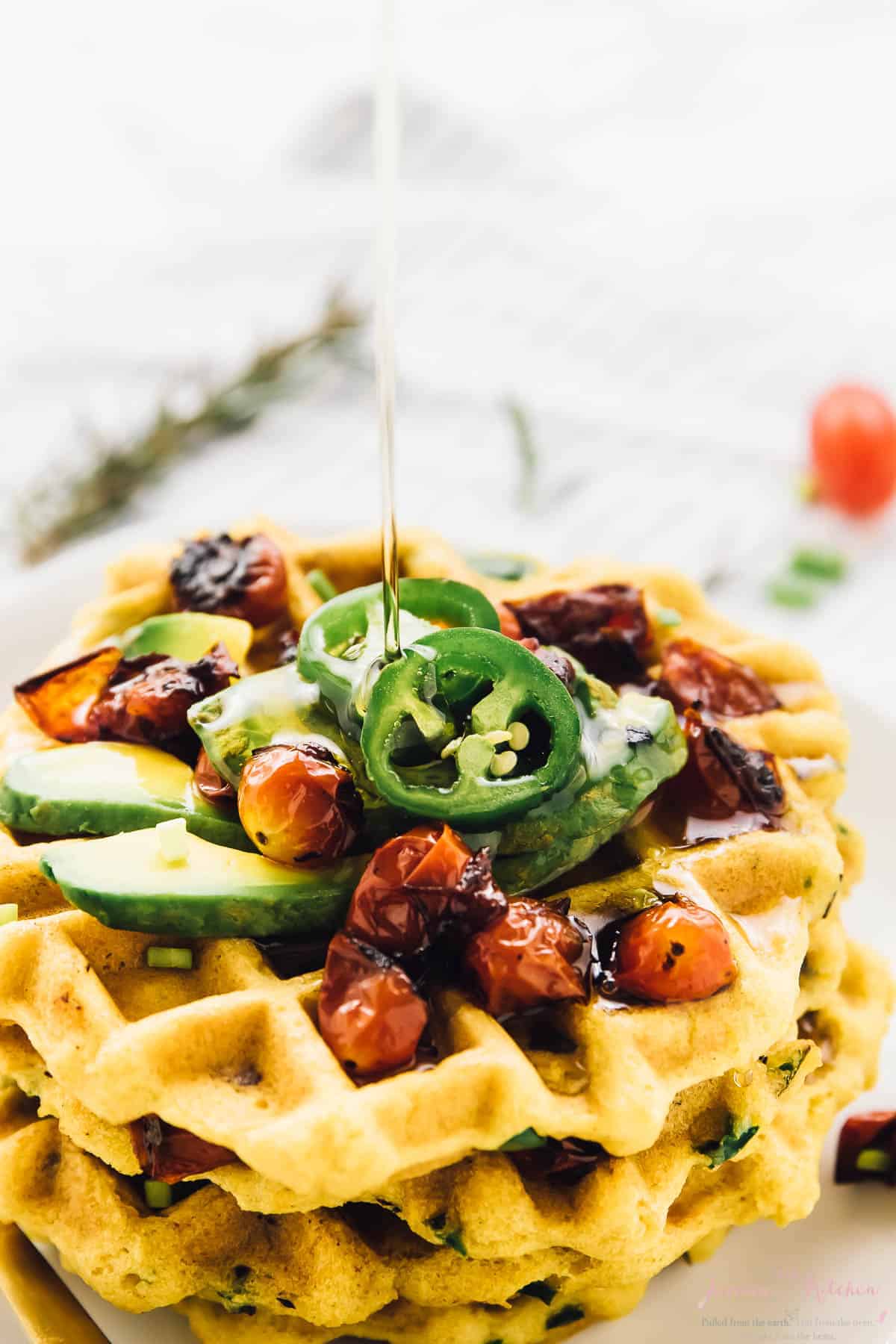 Close up of syrup being drizzled on a stack of cornbread waffles. 