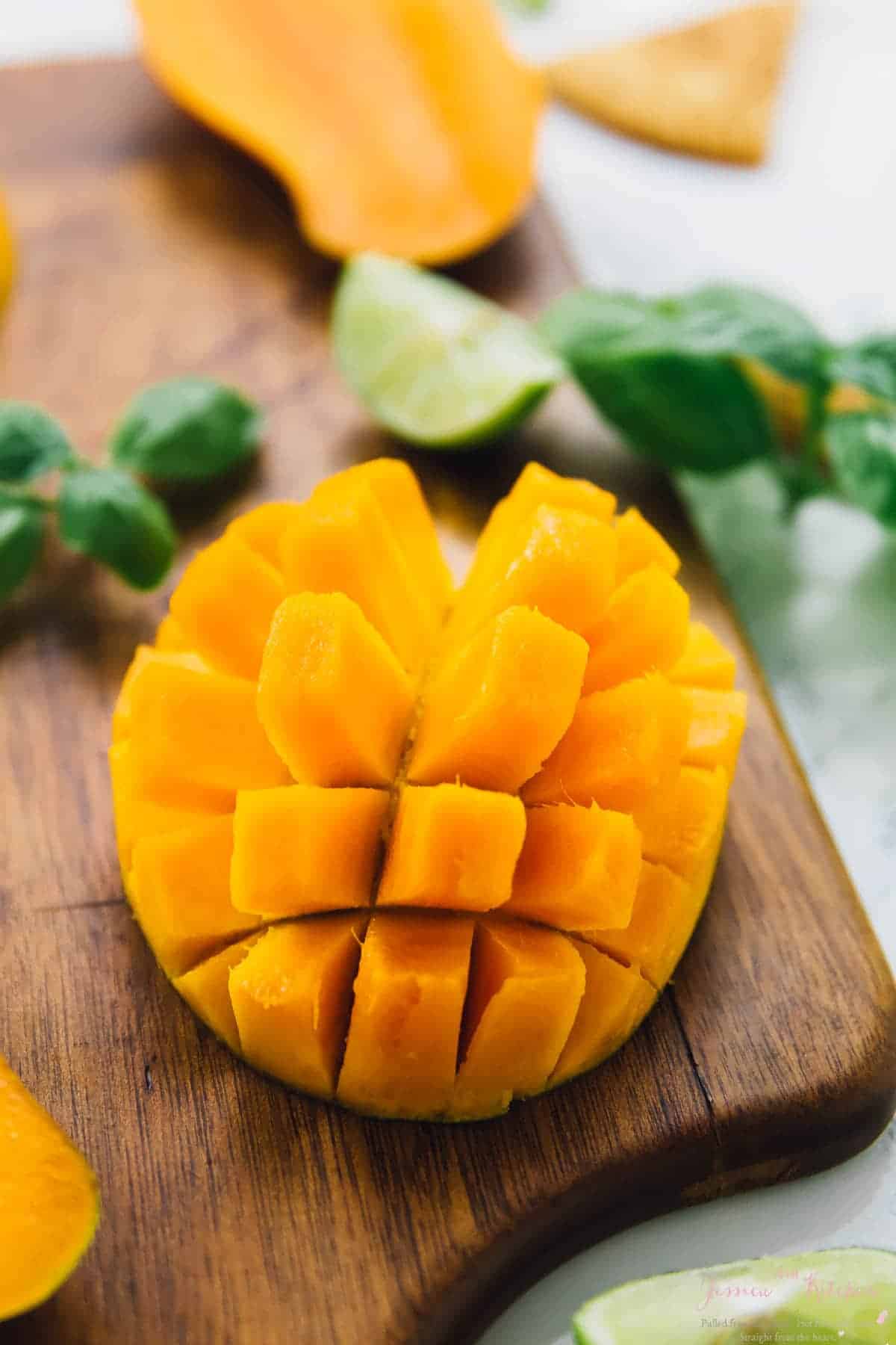 Close up of a cubed mango on a wood board. 