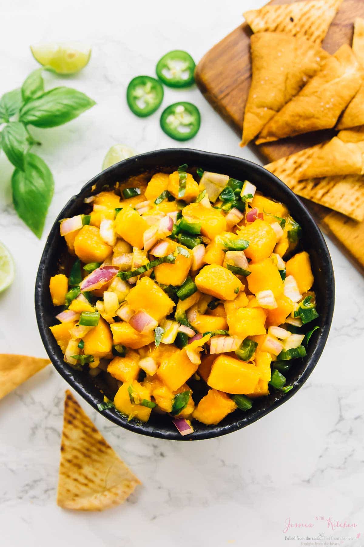 Top down shot of mango basil salsa in a bowl with chips on the side. 