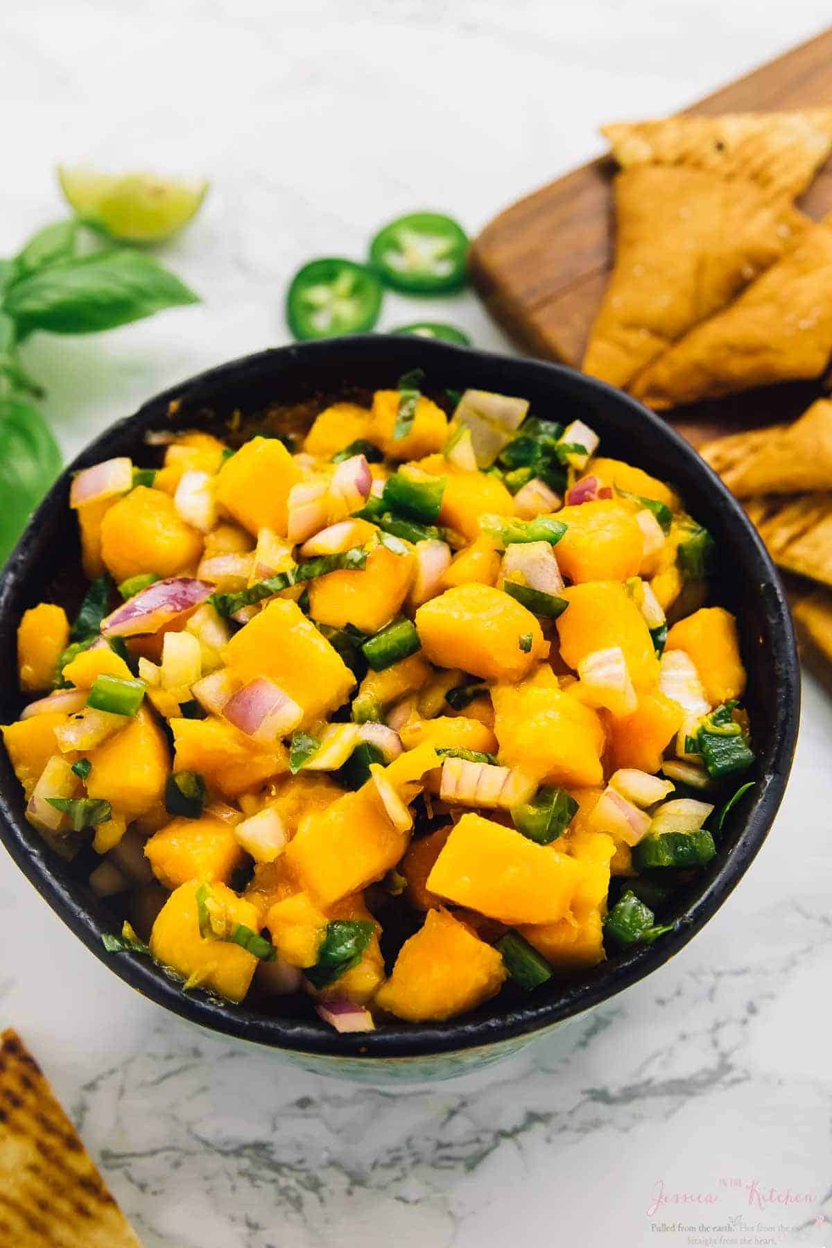 Mango basil salsa in bowl with pita chips in background