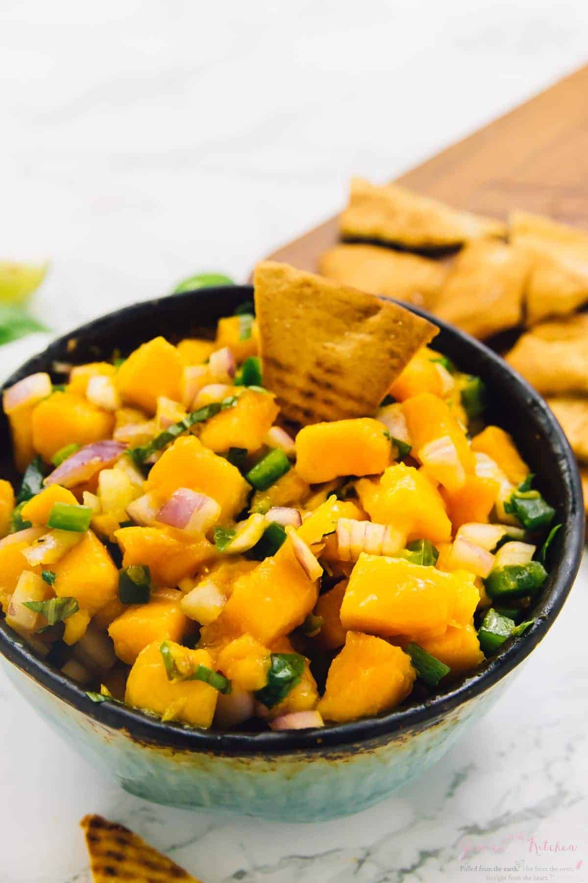 Mango basil salsa in bowl with pita chip