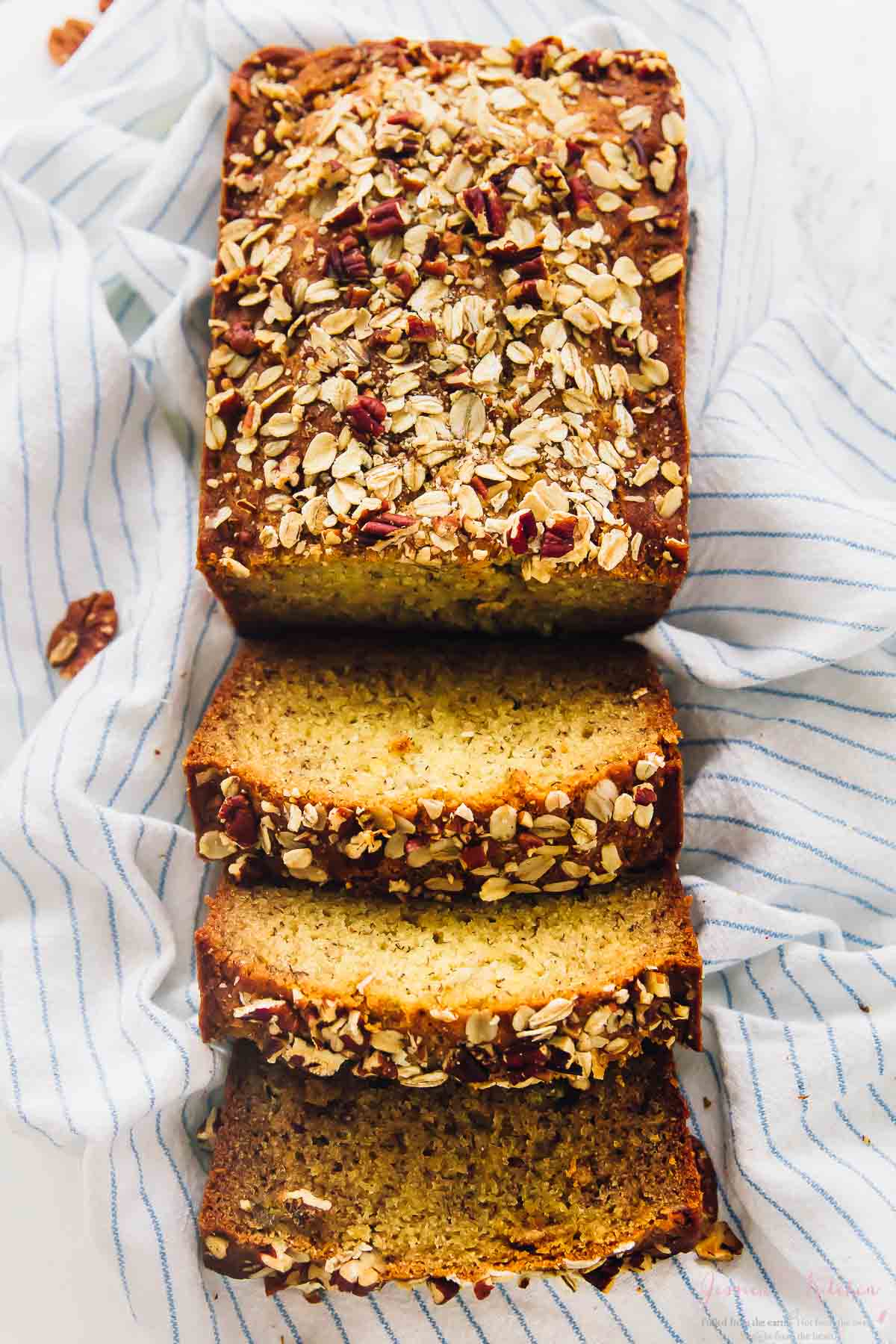 Overhead shot of vegan banana bread cut into slices on a striped cloth.