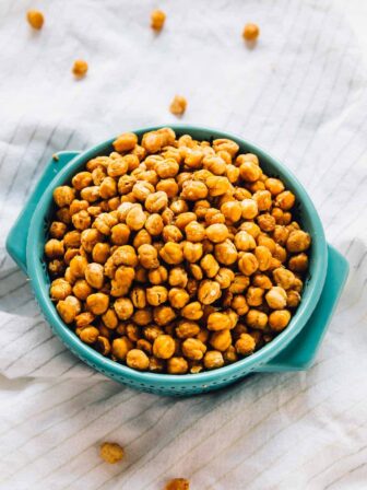 Chickpeas in a blue bowl on a striped cloth.