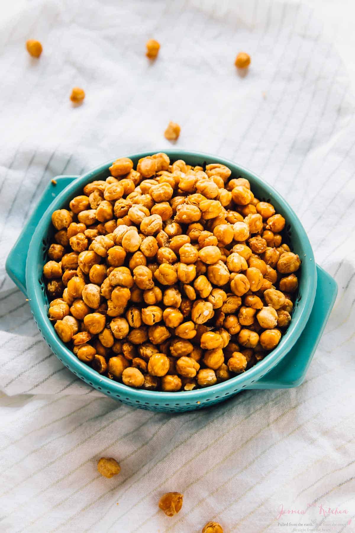 Chickpeas in a blue bowl on a striped cloth.