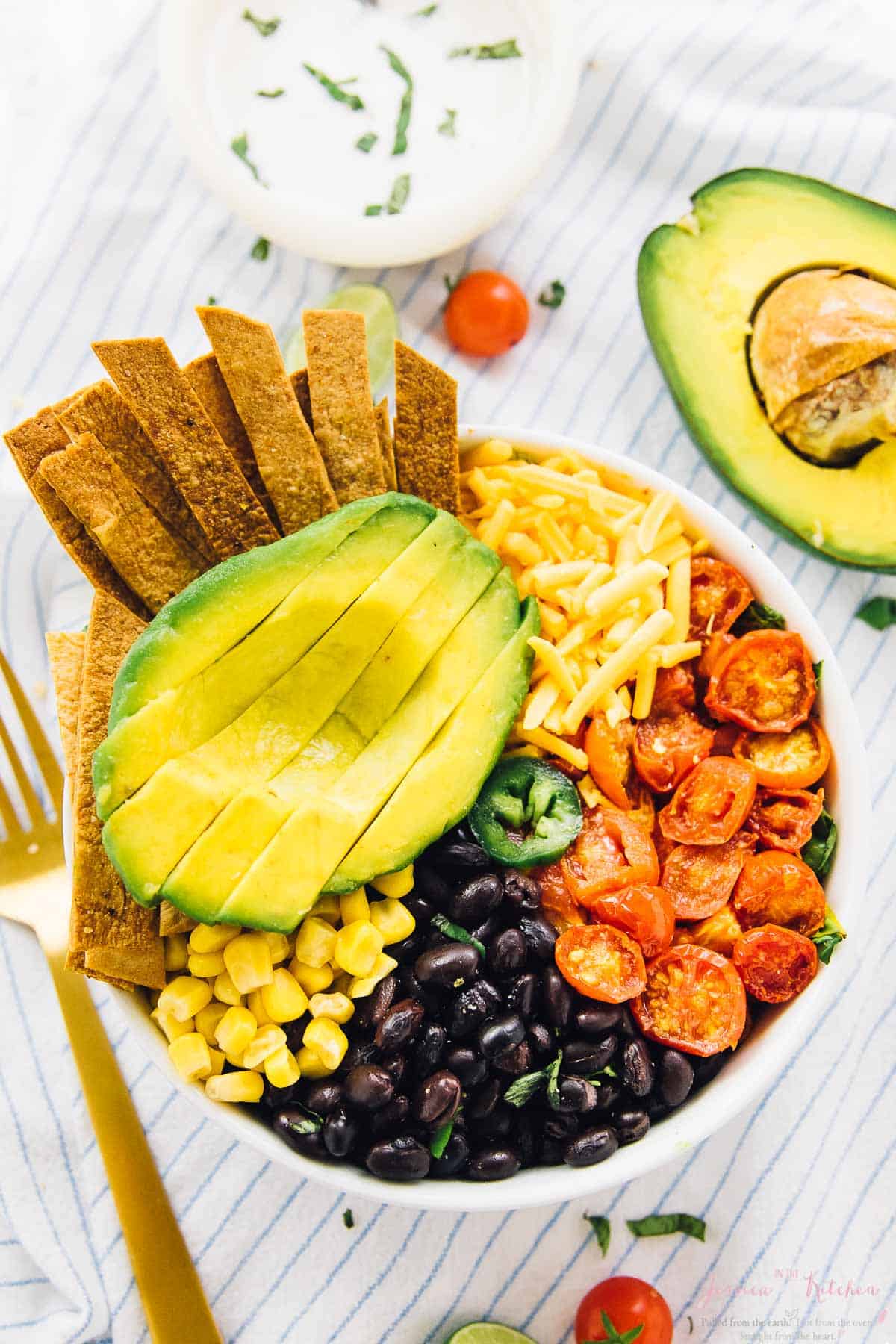 Top down view of a loaded taco salad bowl, topped with sliced avocado.