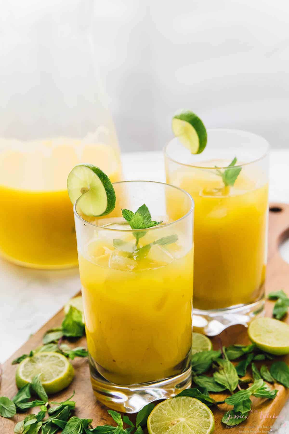 Two glasses of mango mojito with slices of lime. 