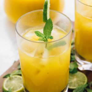 A mango mojito in a glass, garnished with mint and lime.