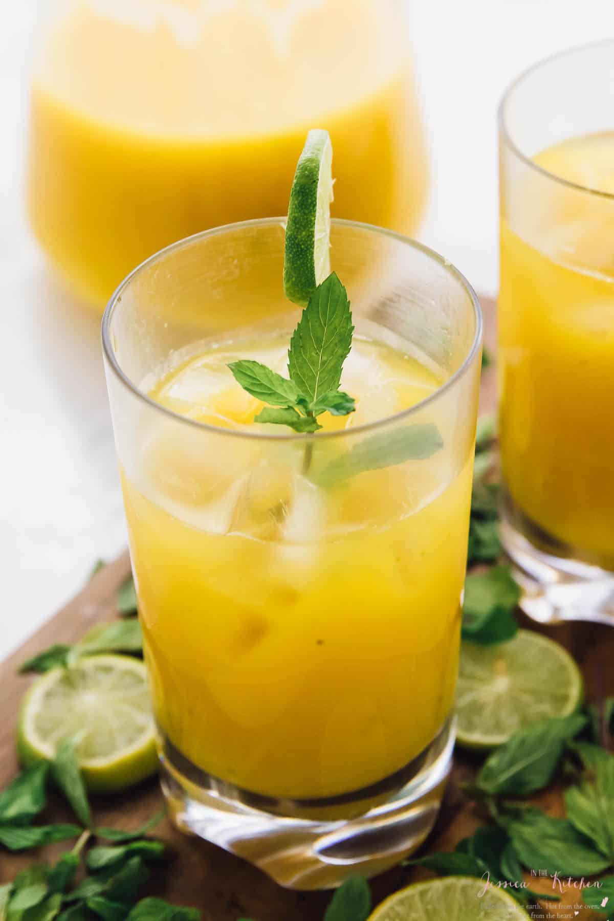 A mango mojito in a glass, garnished with lime and mint.