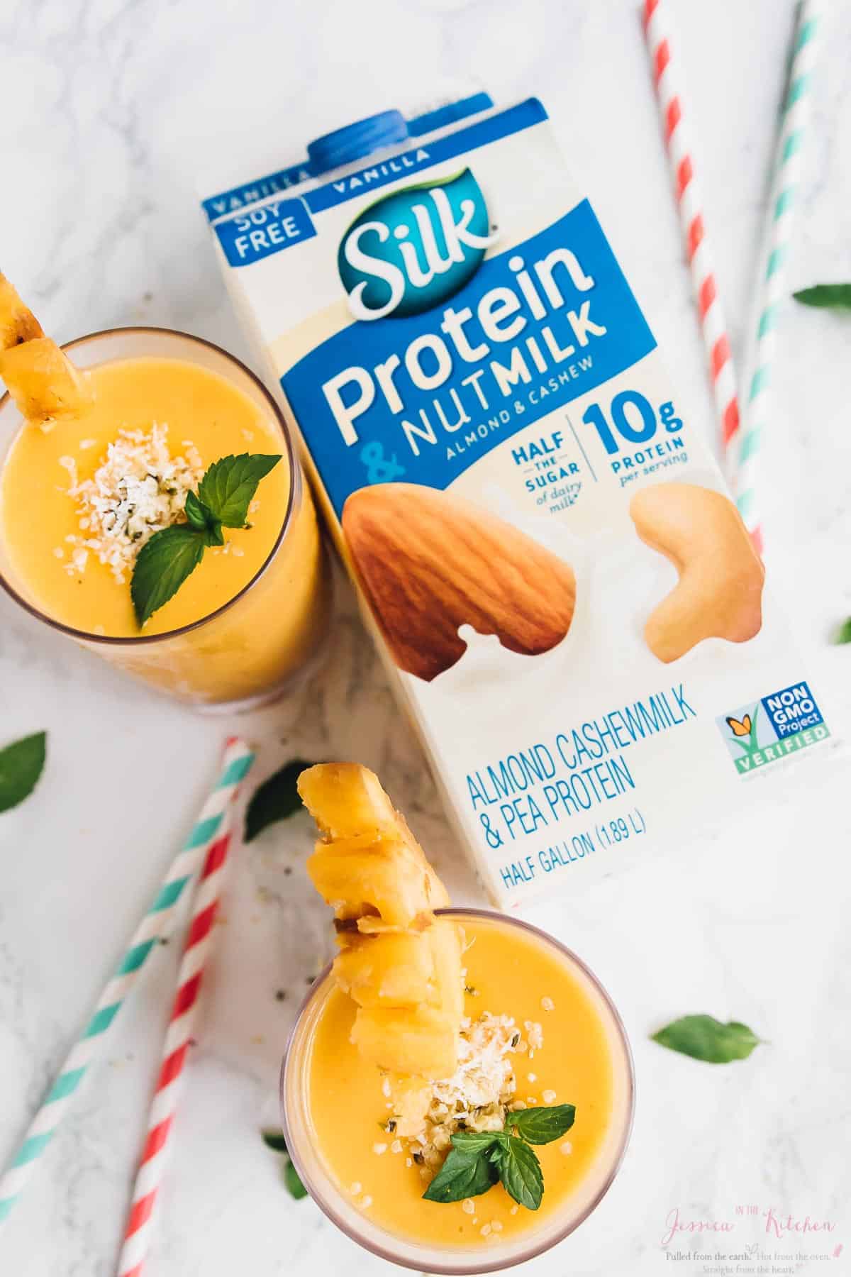 Overhead shot of two pineapple peach smoothies with a carton of nut milk beside them. 