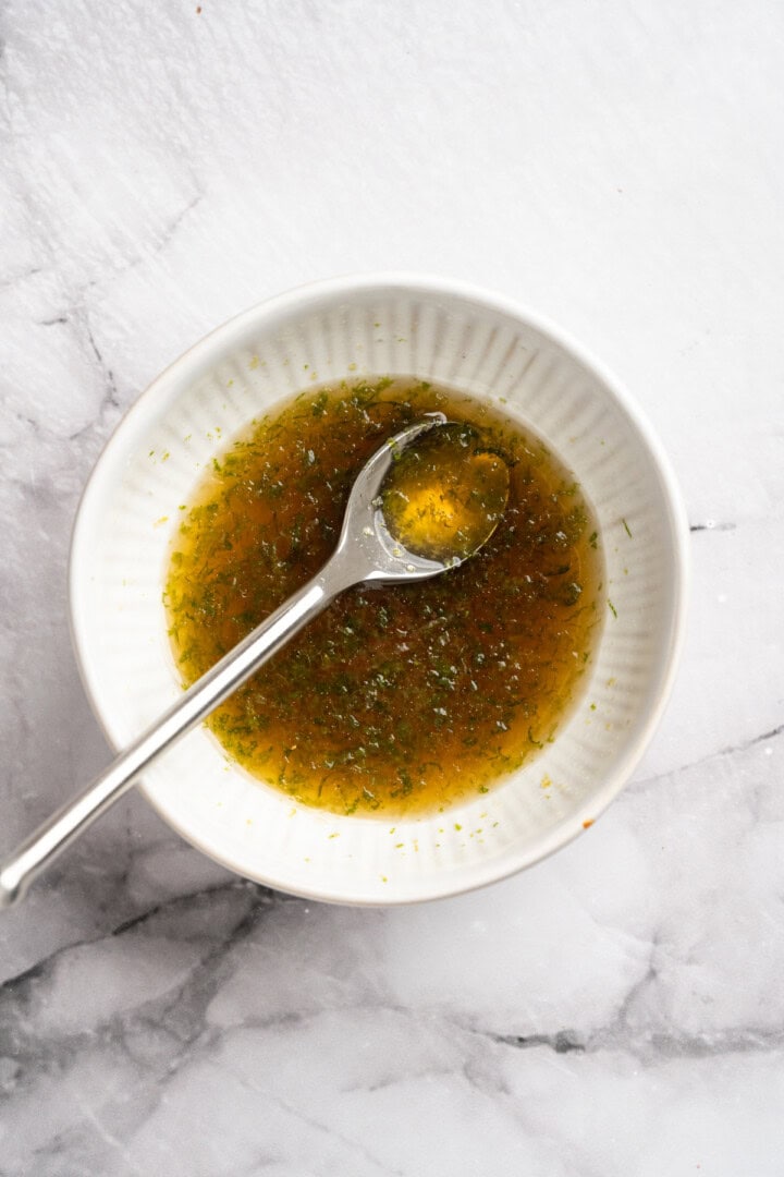 This bright rainbow fruit salad is tossed in a fresh maple lime dressing for a side that's juicy, refreshing, and perfect for any occasion! Maple lime dressing in bowl with spoon.