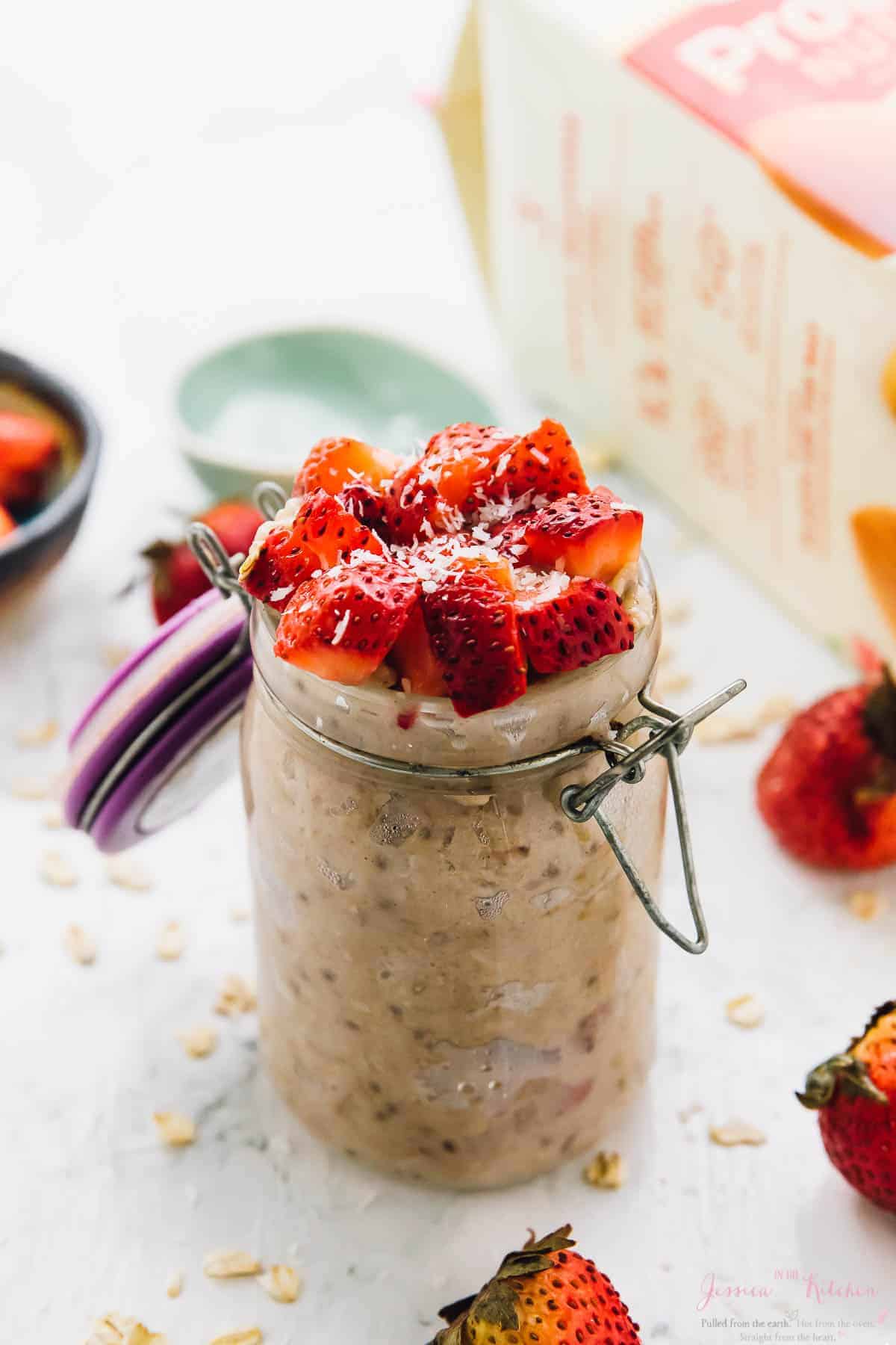 Jar of strawberry coconut overnight oats topped with fresh berries and coconut