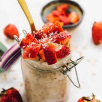 Overnight oats in a glass jar with a gold spoon in it.