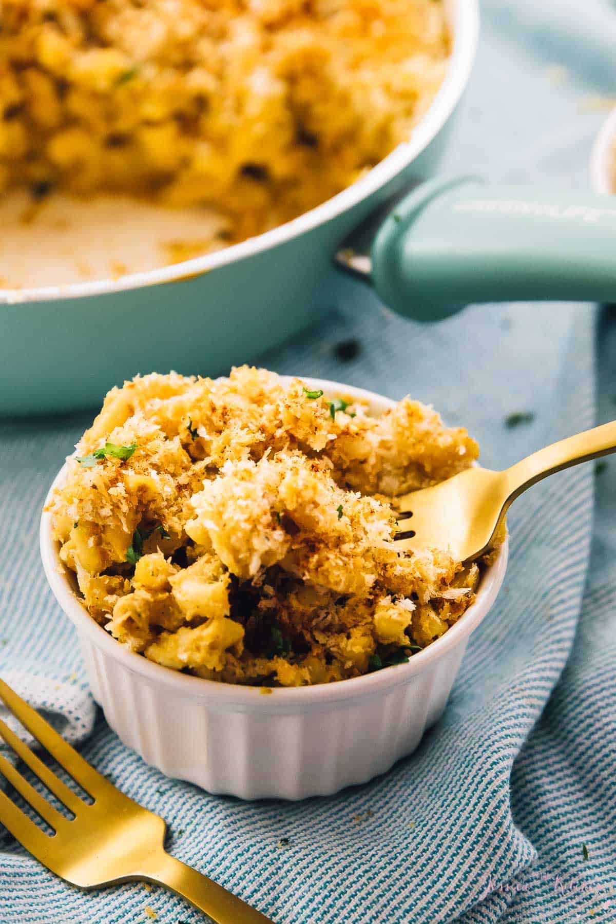 Fork scooping out mac and cheese from a white ramekin.