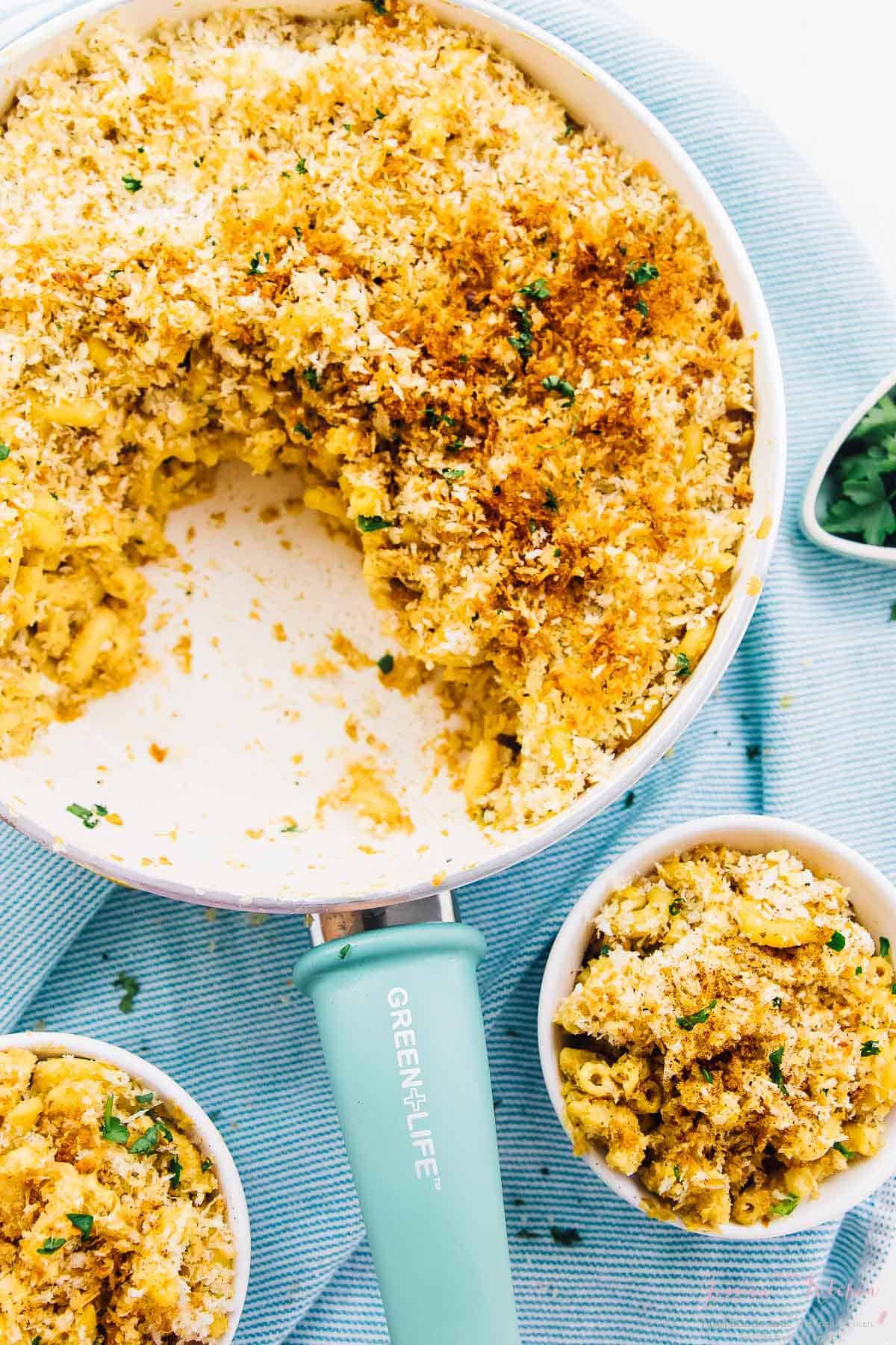 Overhead view of baked vegan mac & cheese in a skillet and two bowls. 