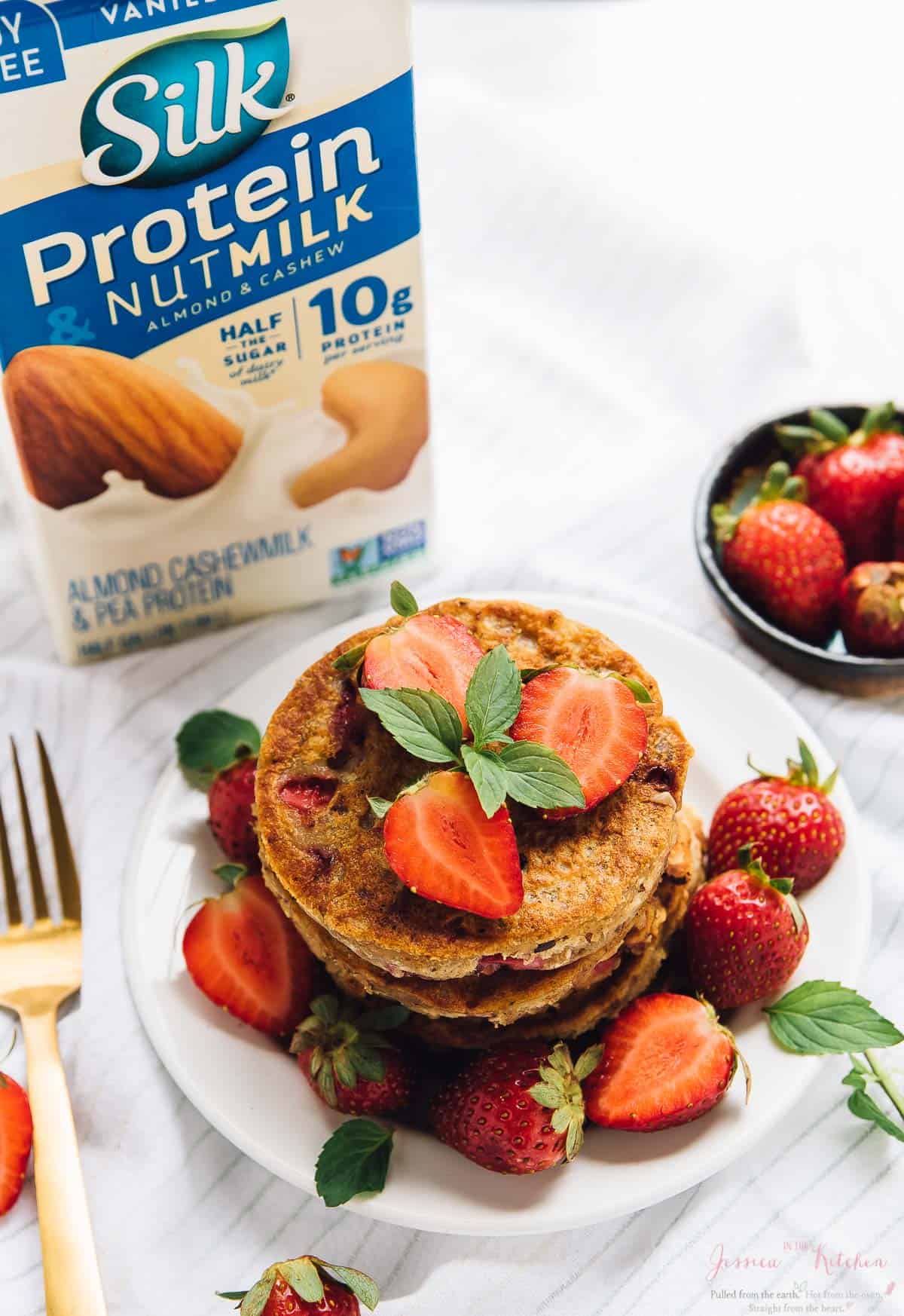 Overhead view of gluten free strawberry pancakes with a carton of nut milk in the background. 