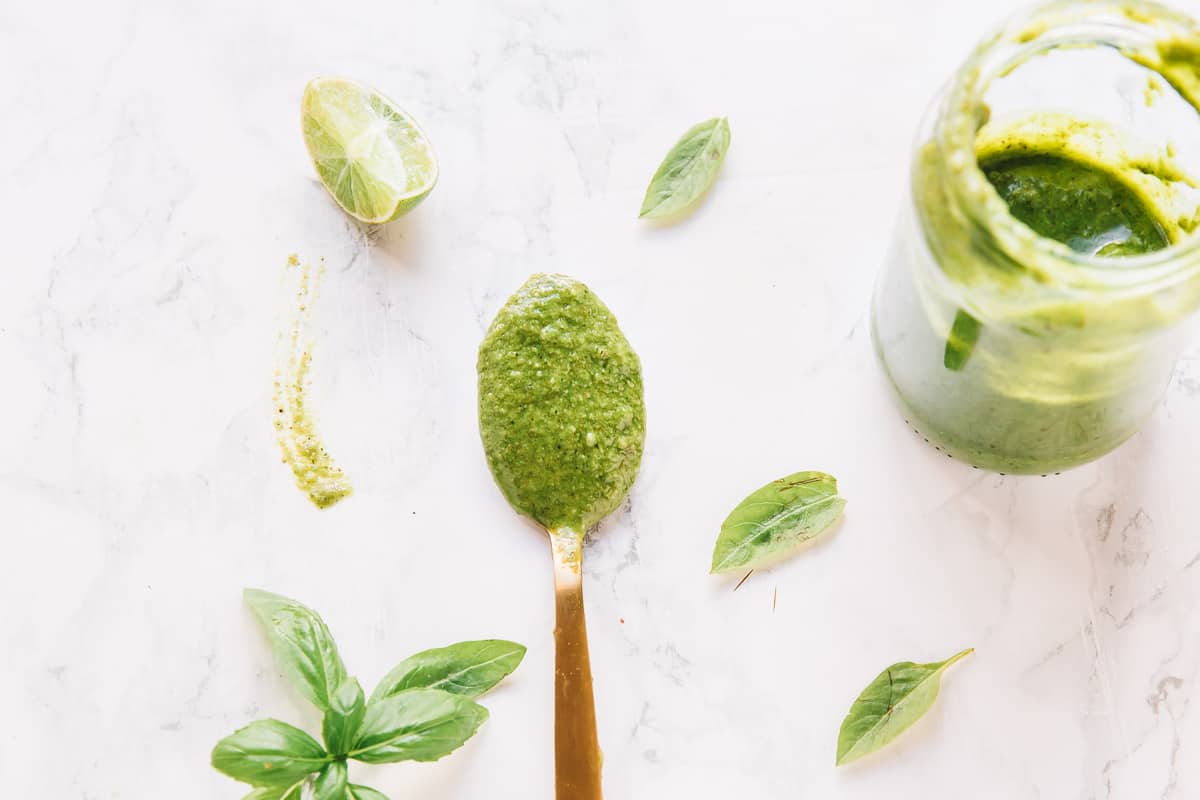 Top down shot of basil pesto on a gold spoon.