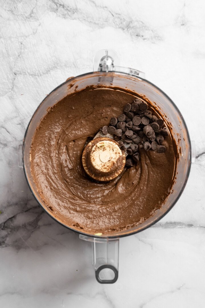 Chocolate chips added to chocolate avocado pudding in food processor bowl.