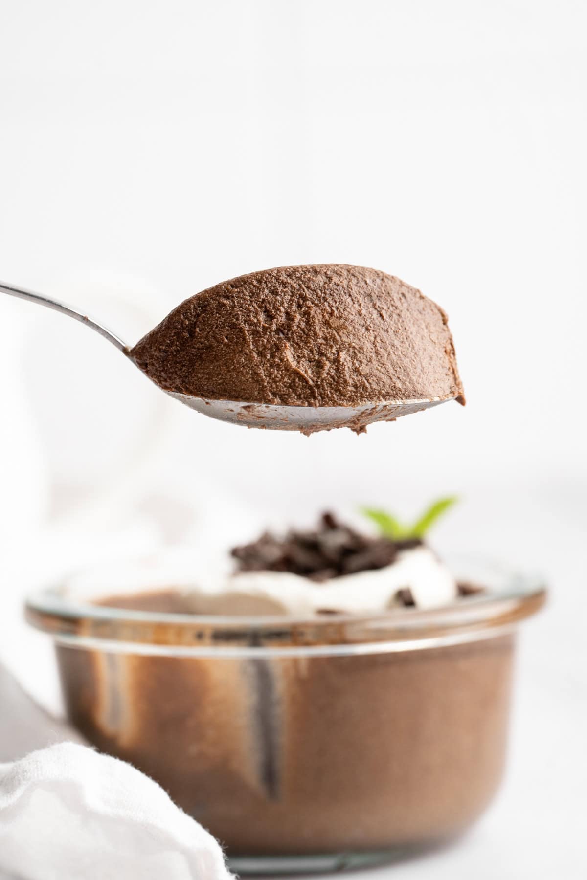 Spoonful of thick, creamy chocolate avocado pudding held over bowl.