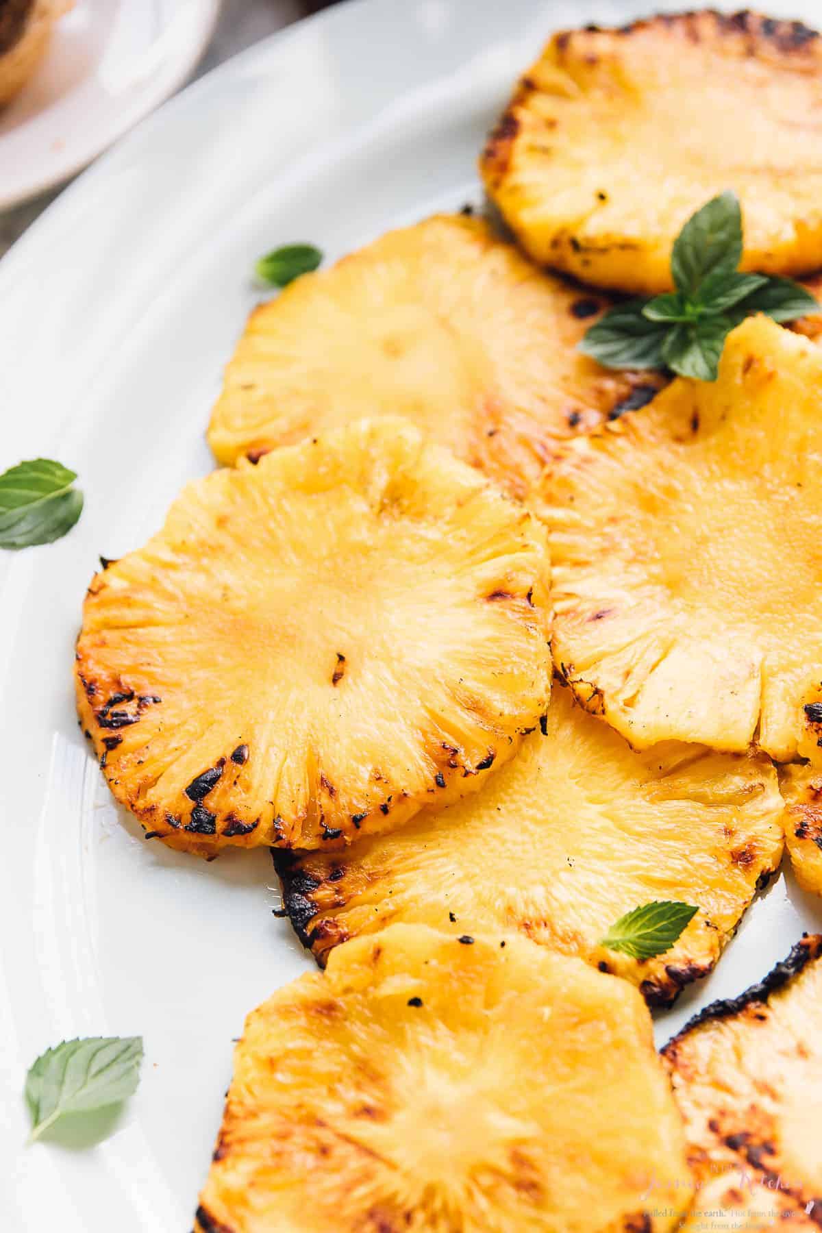 Slices of grilled pineapples on a white dish.