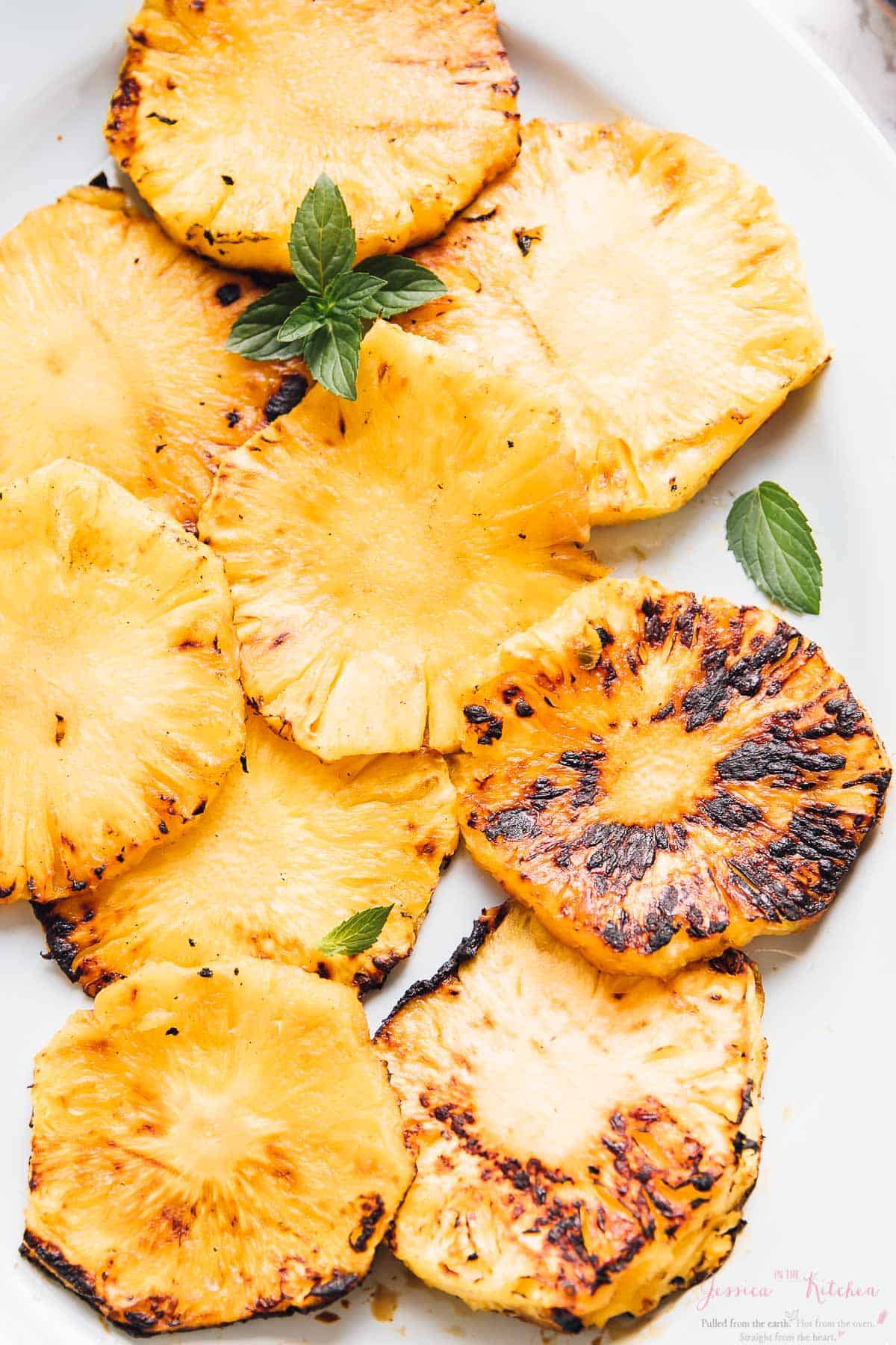Top down shot of grilled pineapples on a white dish.