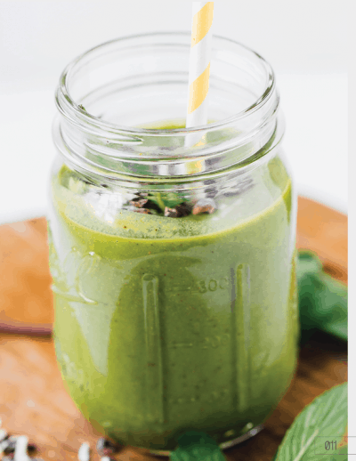 Mint chocolate chip smoothie in a mason jar with a yellow straw.
