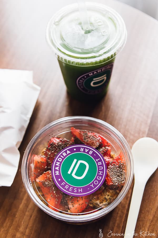 Top down shot of strawberry yogurt in a tub with a green drink next to it. 