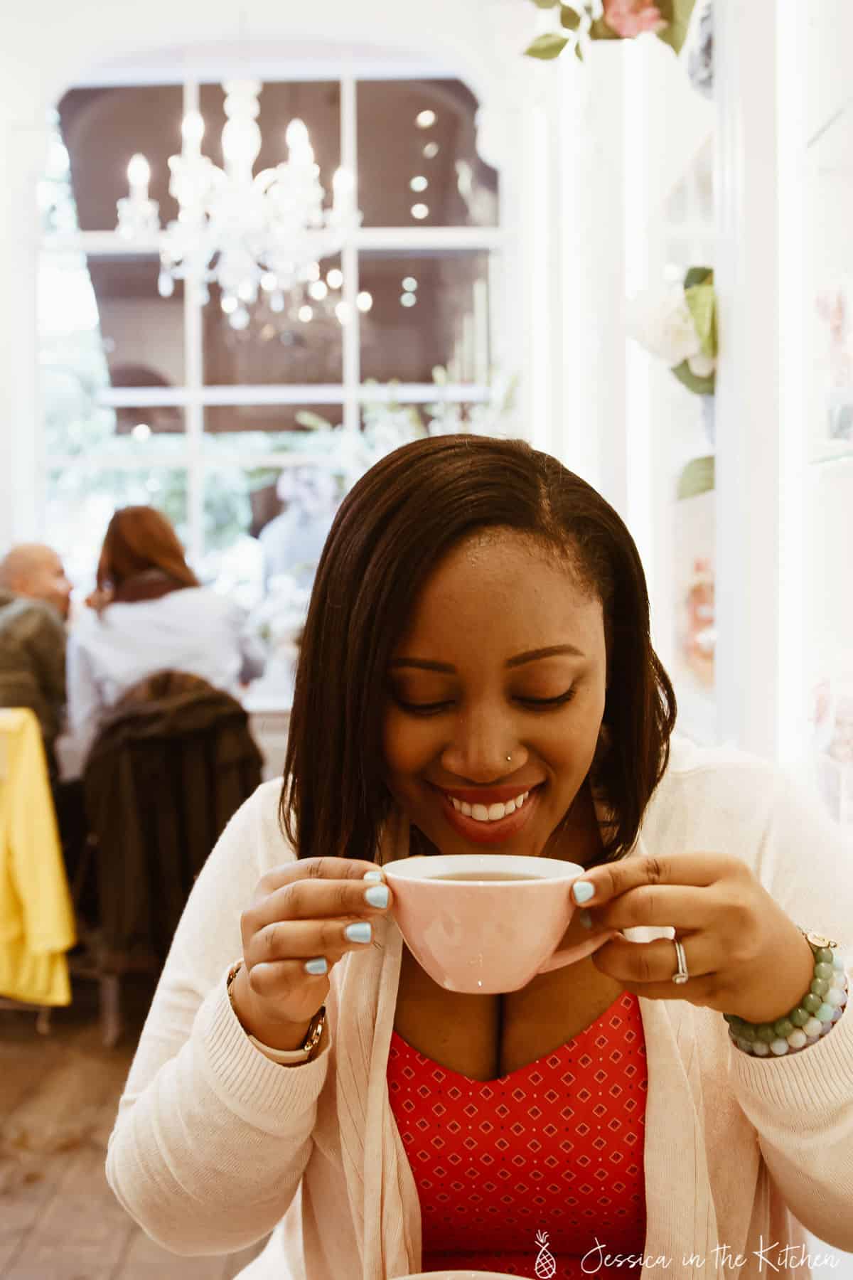 Jessica drinking a cup of coffee in a restaurant. 