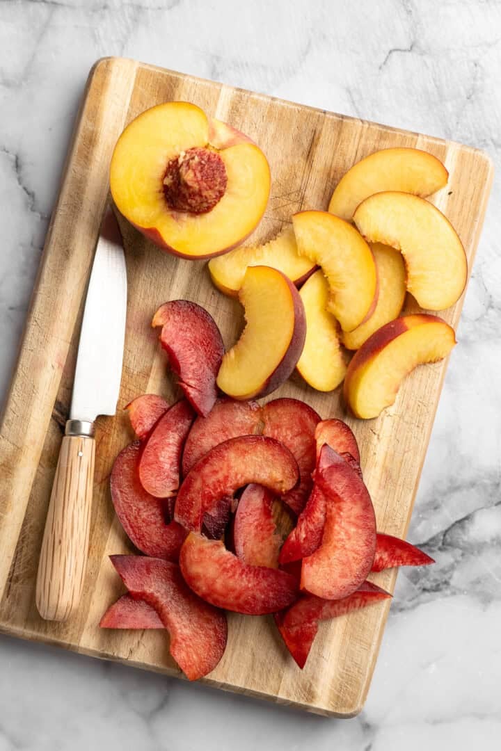 Sweet, juicy summer fruit and fluffy quinoa come together in this beautiful quinoa stone fruit salad. It’s ready in just 20 minutes! Peaches and plums sliced on board with knife.
