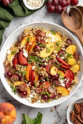 Quinoa salad in bowl with peaches, plums, and grapes.