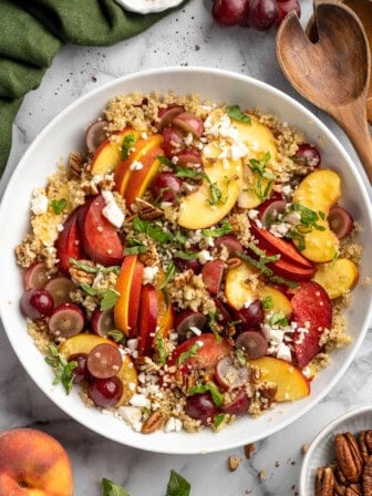 Quinoa salad in bowl with peaches, plums, and grapes.