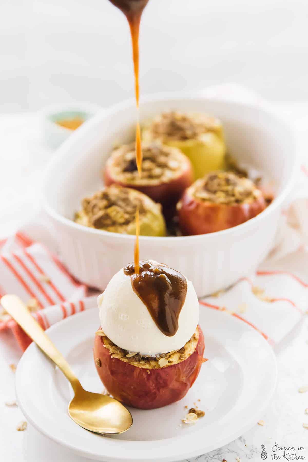 Pouring sauce on a baked apple with baked apples in the background. 