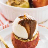 A baked apple covered in ice cream and sauce.