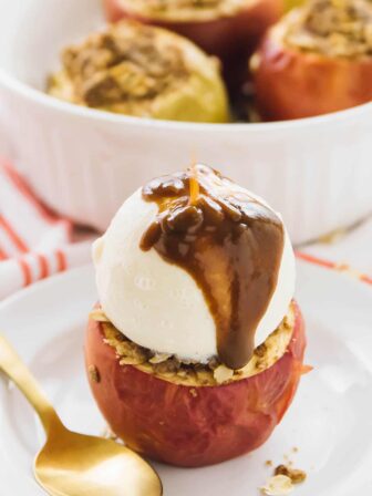 A baked apple covered in ice cream and sauce.